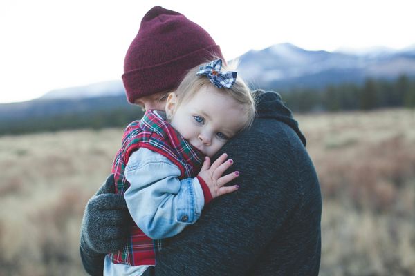 Un homme tient une petite fille dans ses bras.