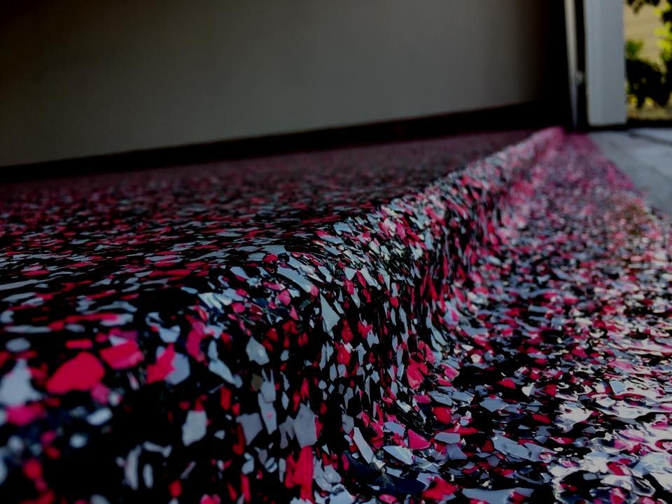 Garage floor with red, black, and white flakes, showing a curved, textured edge near the opening.