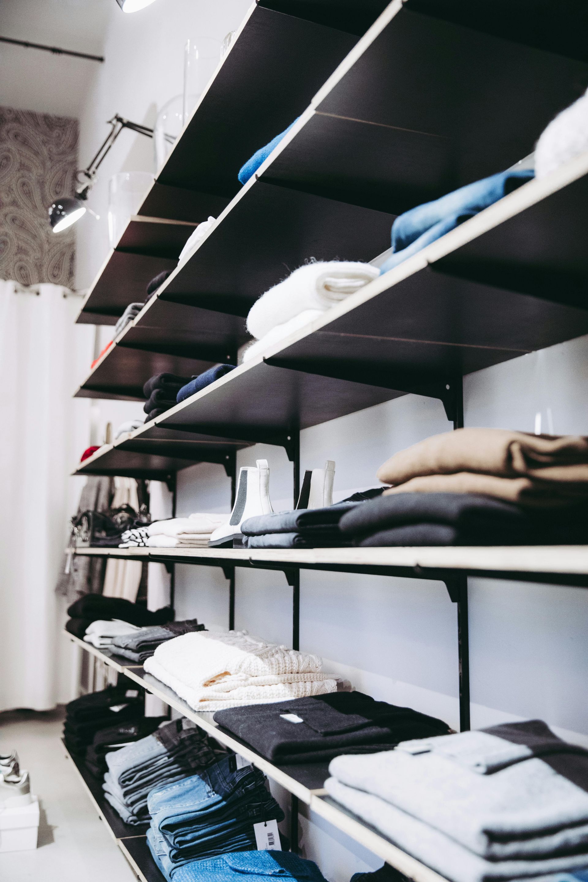 Clothes neatly folded on dark shelves in a retail store.