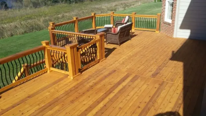 A large wooden deck with chairs and a table on it