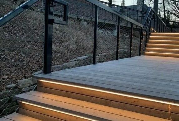 A wooden deck with stairs leading up to it and a railing.