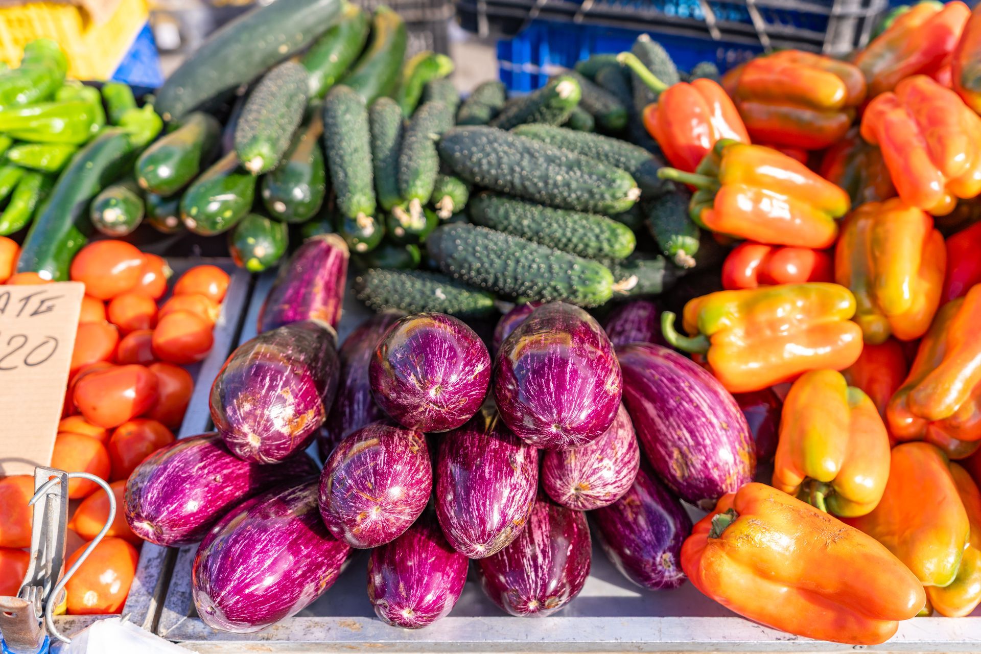 Vegetables for sale: tomatoes, zucchini, cucumbers, eggplants, and bell peppers in a market.