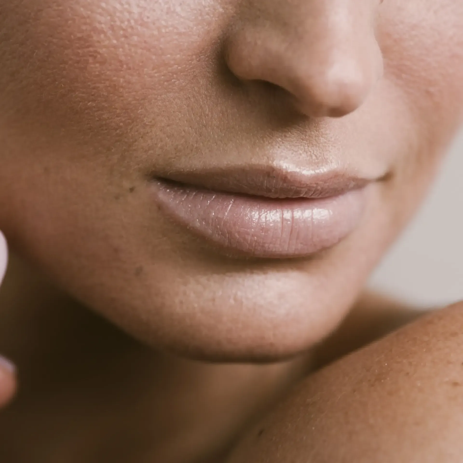A close-up view of a person's mouth and nose, showcasing natural skin texture and lips with a subtle gloss.