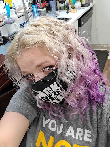 A woman wearing a mask and glasses is taking a selfie in a kitchen.