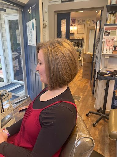 A woman is sitting in a chair in a salon getting her hair cut.