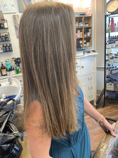 A woman in a blue dress is getting her hair cut in a salon.