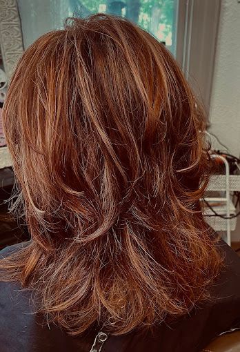 A woman with long red hair is sitting in a chair.