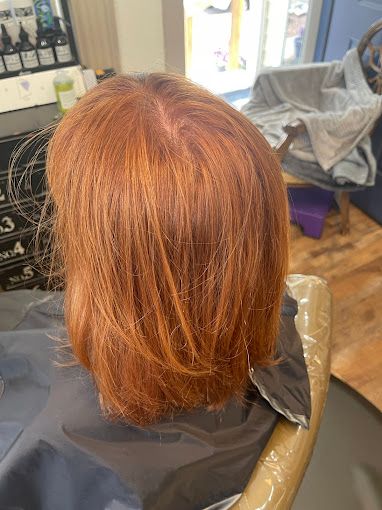 A woman with red hair is sitting in a chair in a salon.