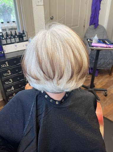 A woman is sitting in a chair with her hair cut in a salon.