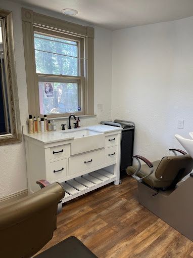 A room with a sink , chair , mirror and window.