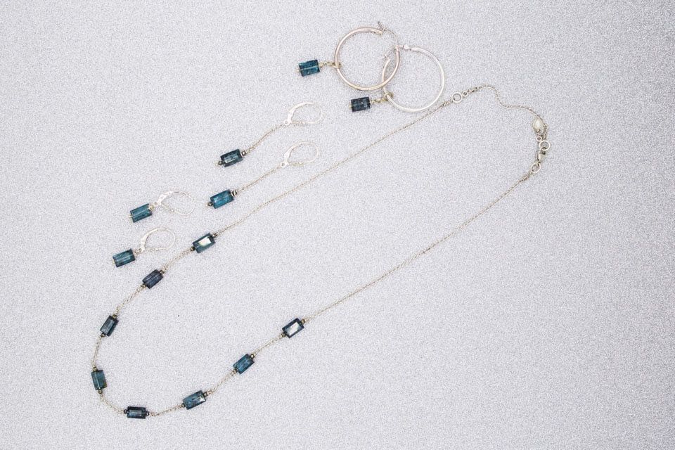 A necklace and earrings are sitting on a white surface.