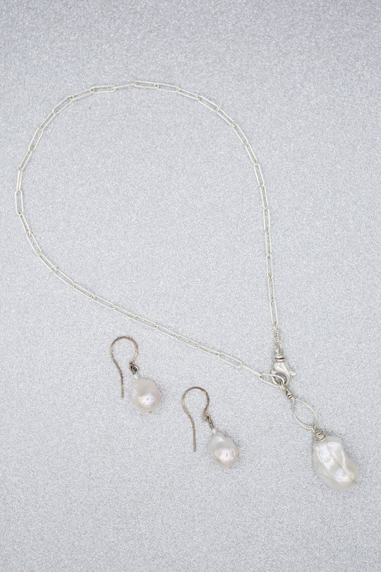 A close up of a necklace and earring set on a white surface.