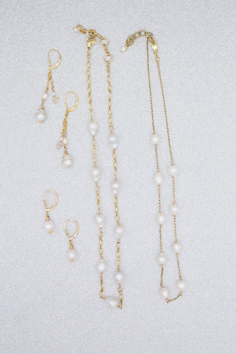 A necklace and earring set with pearls on a white surface.
