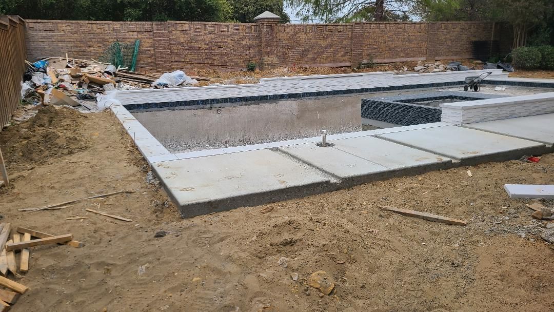 A large swimming pool is being built in a backyard.