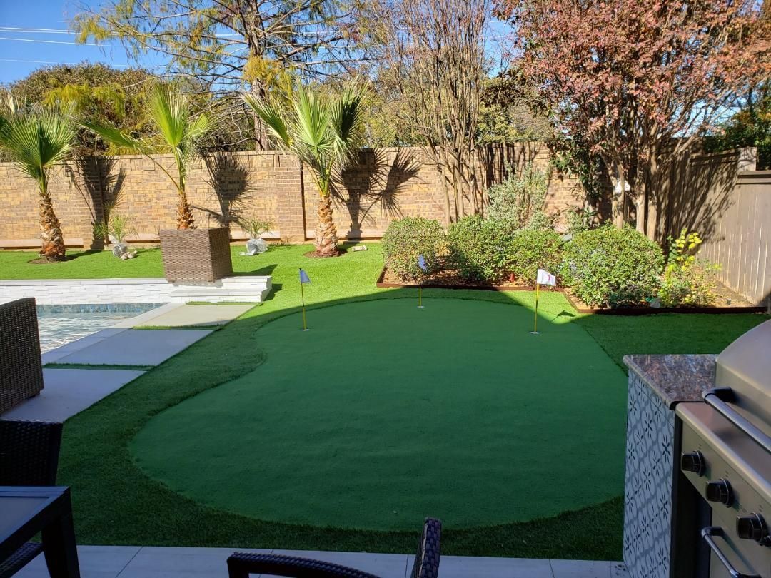 There is a putting green in the backyard of a house.