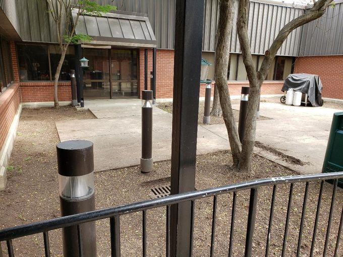 A fence surrounds a courtyard with a brick building in the background