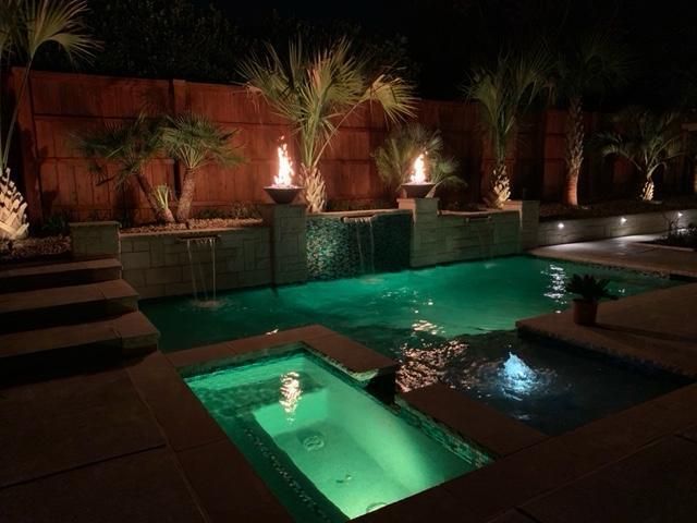 A large swimming pool is lit up at night with green lights.