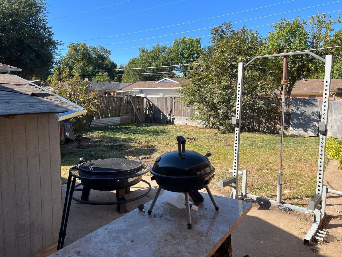 A small grill is sitting on a table in a backyard.