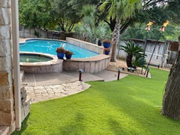 There is a large swimming pool in the backyard of a house.