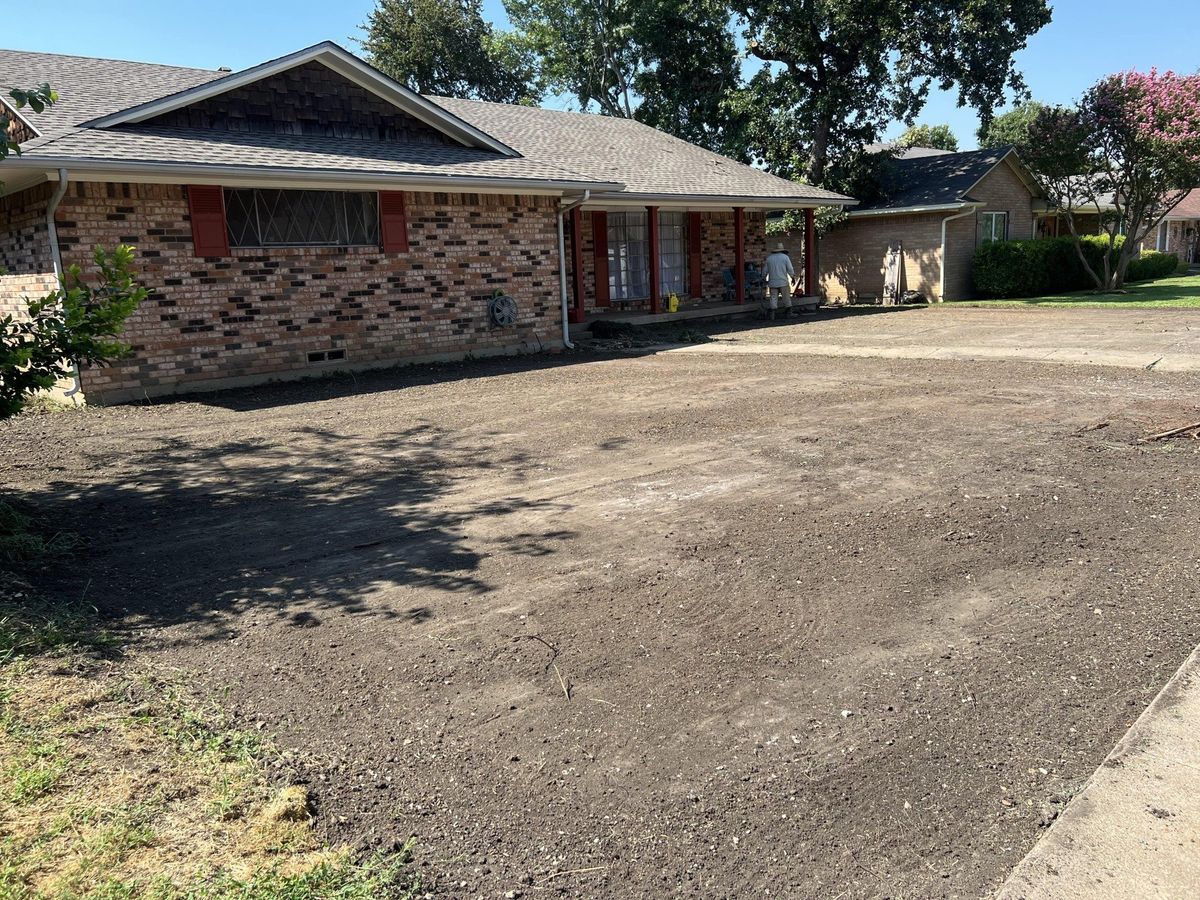 A brick house with a dirt driveway in front of it.