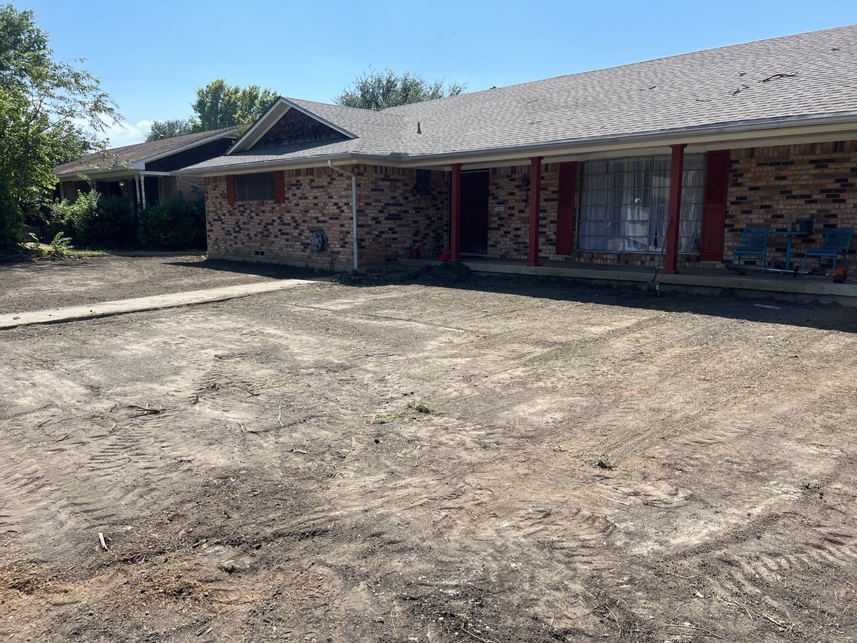 A brick house with a dirt driveway in front of it.