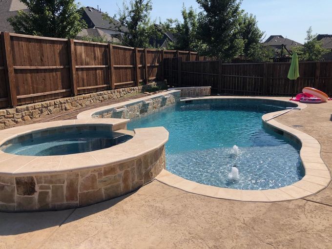 A large swimming pool with a hot tub in the backyard.