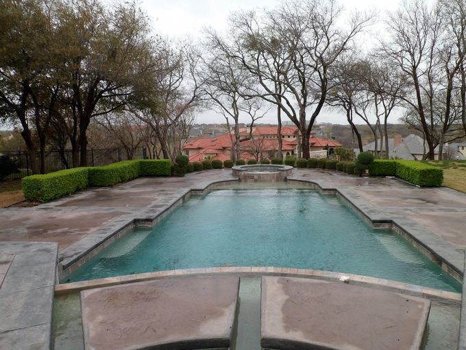 A large swimming pool surrounded by trees and bushes