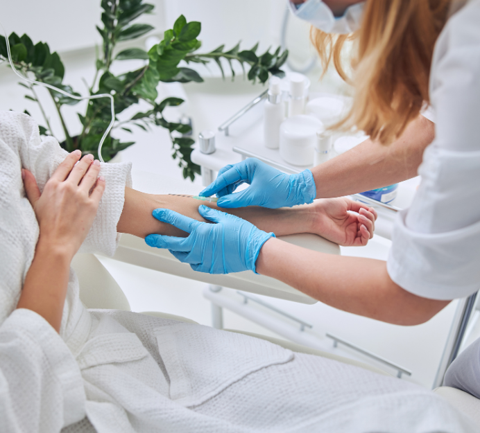 Woman with short blonde hair, smiling, looking upward; wearing a black top and beige vest.