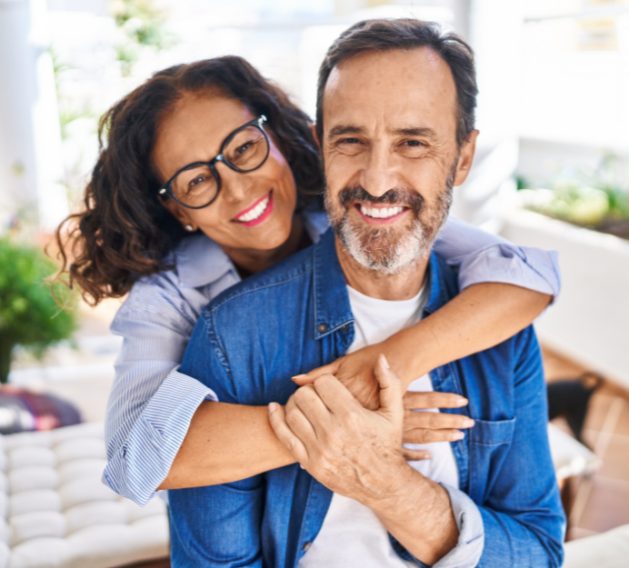 Woman embracing a smiling man outdoors; both are smiling and looking at the camera.