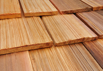 Two roofers installing shingles on a roof, with some new shingles and vents visible.
