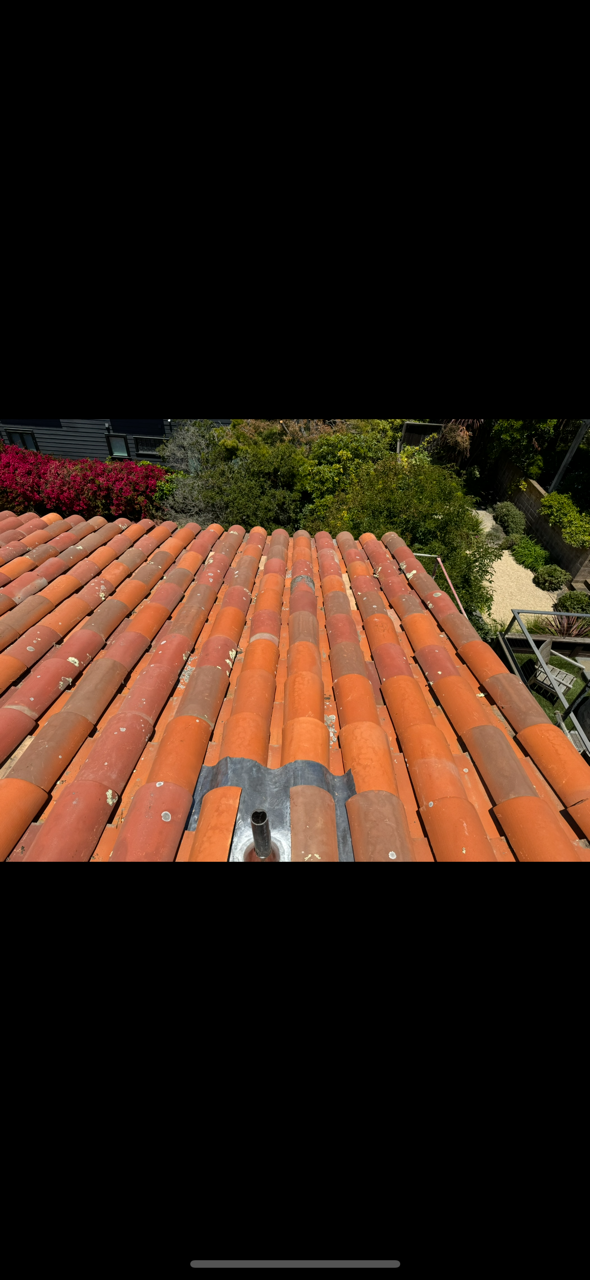 Wooden shingle roof with aged, weathered appearance against a clear blue sky.