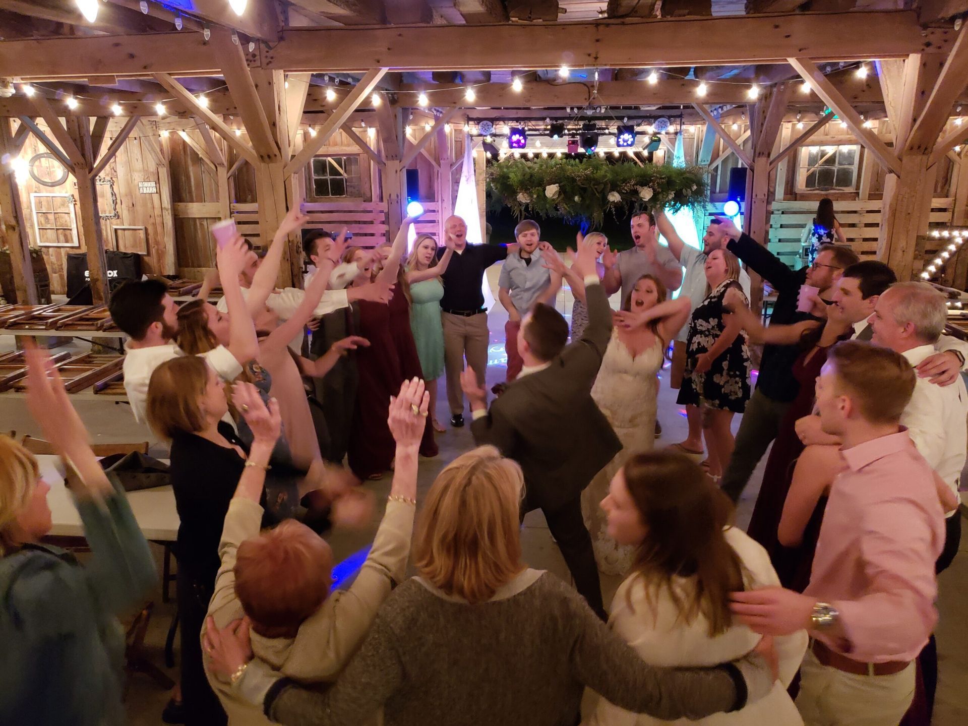 A large group of people are dancing in a barn.