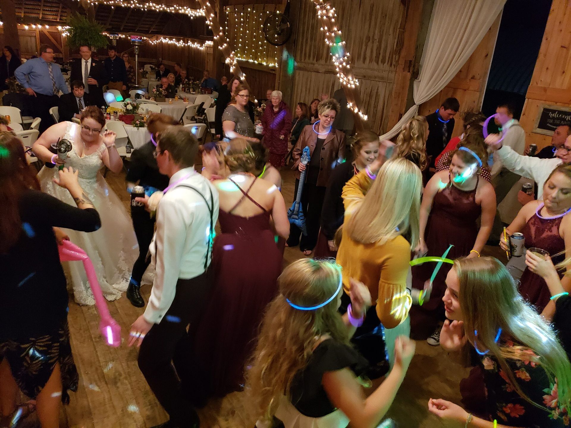 A large group of people are dancing at a wedding reception.