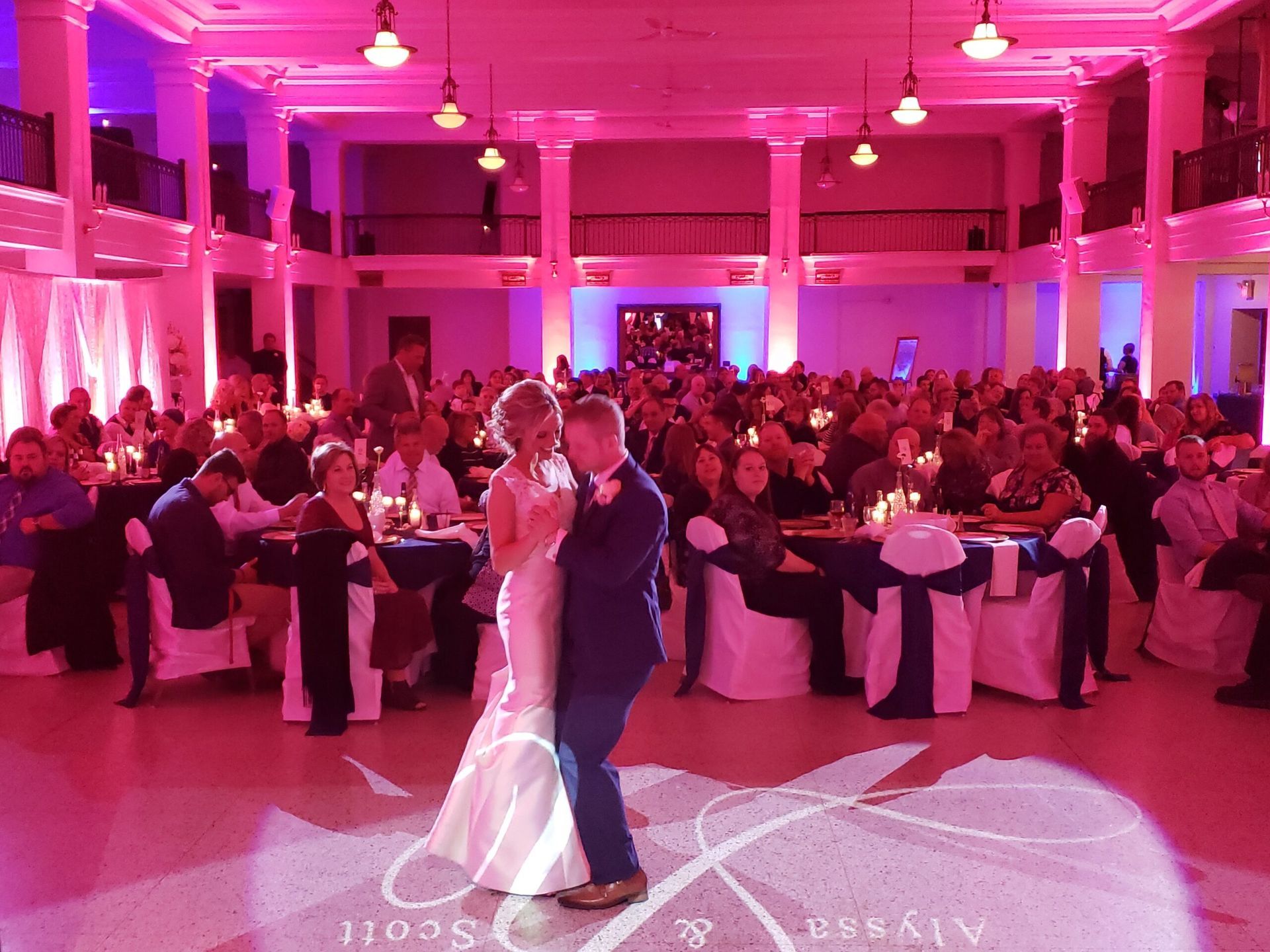 A bride and groom are dancing in front of a crowd at their wedding reception