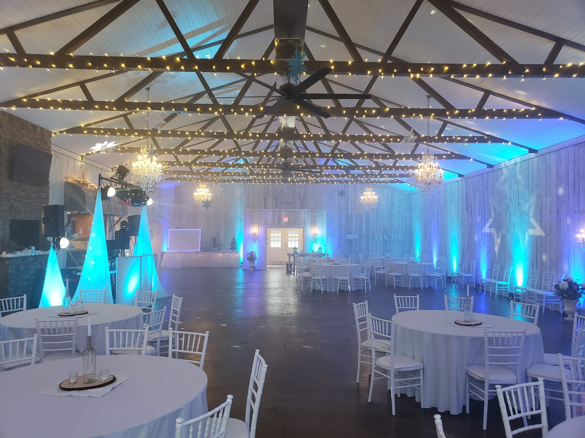 A large room with tables and chairs set up for a wedding reception.