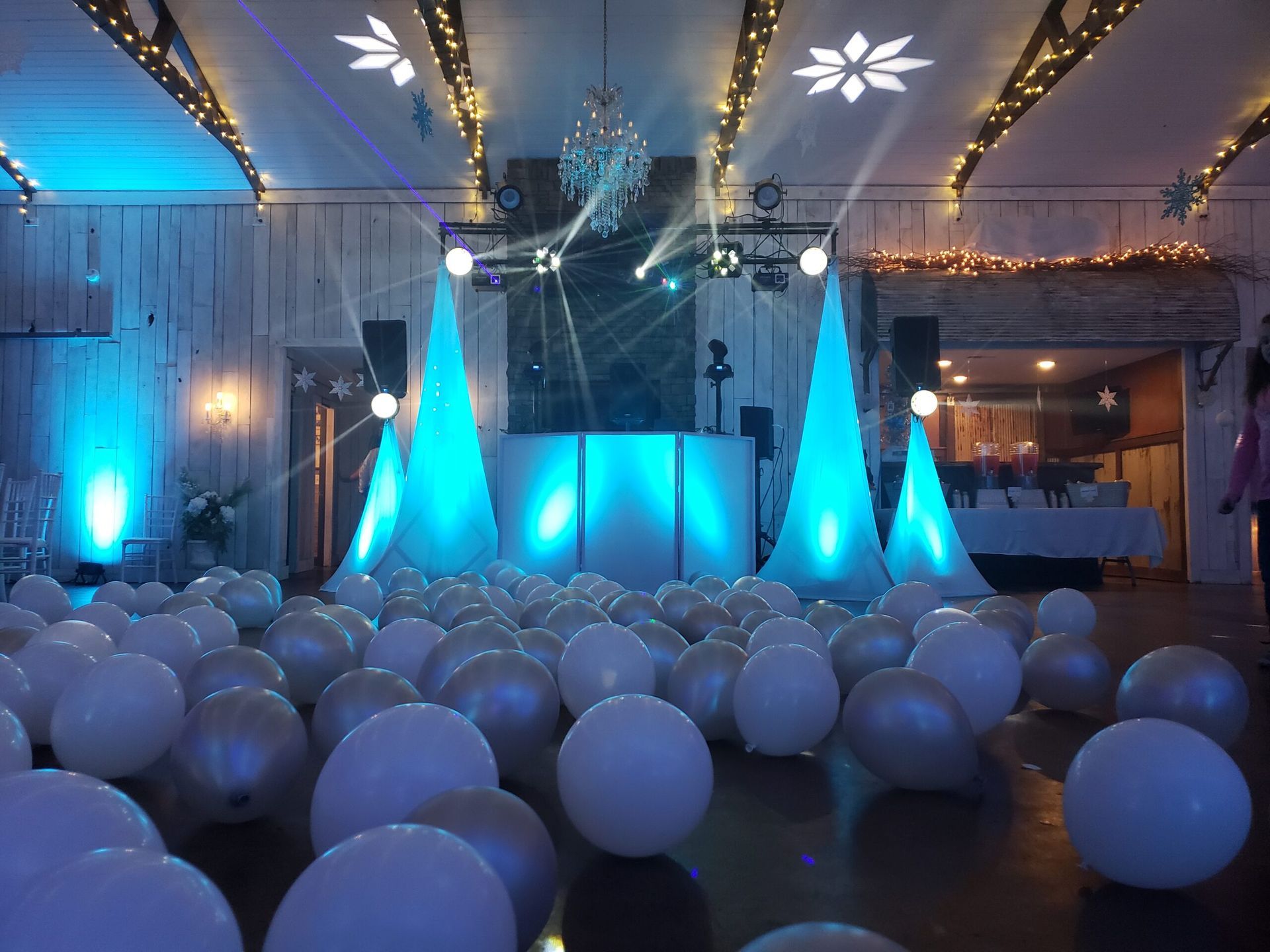 A room filled with lots of white balloons and a dj booth.