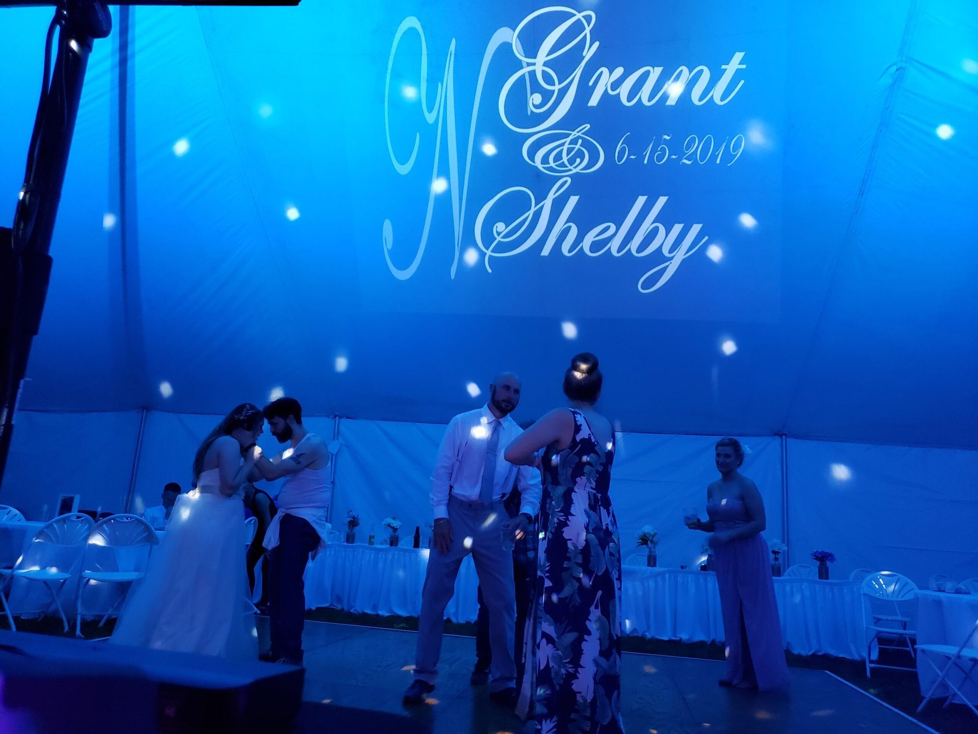 A bride and groom are dancing under a tent at their wedding reception.