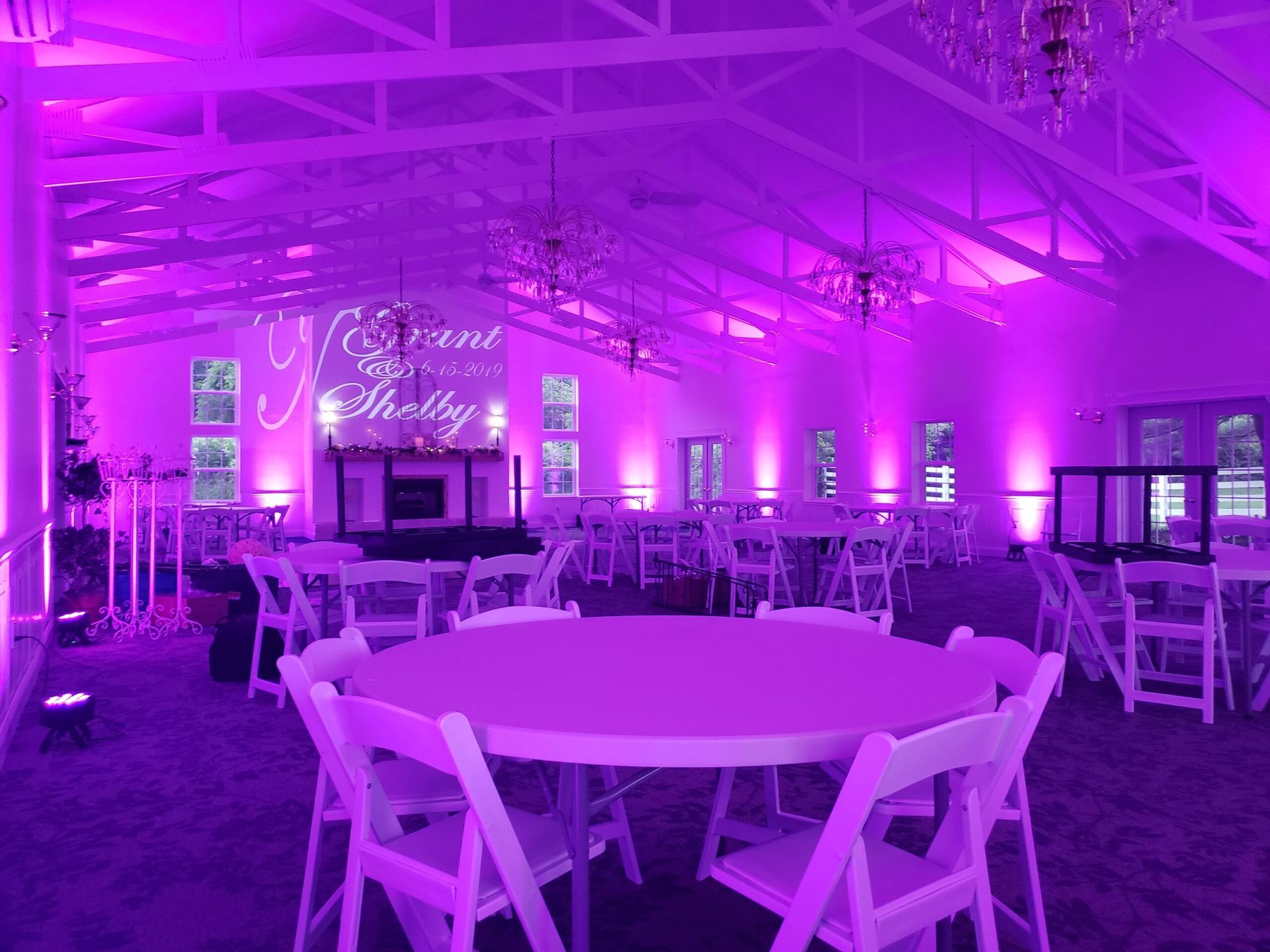 A large room with purple lights on the ceiling and tables and chairs.