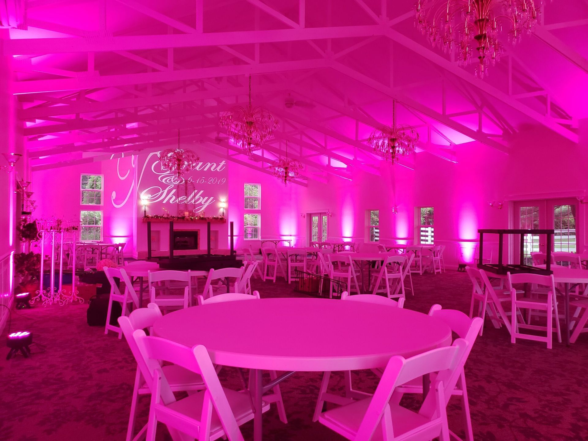 A large room with pink lights on the ceiling and tables and chairs.