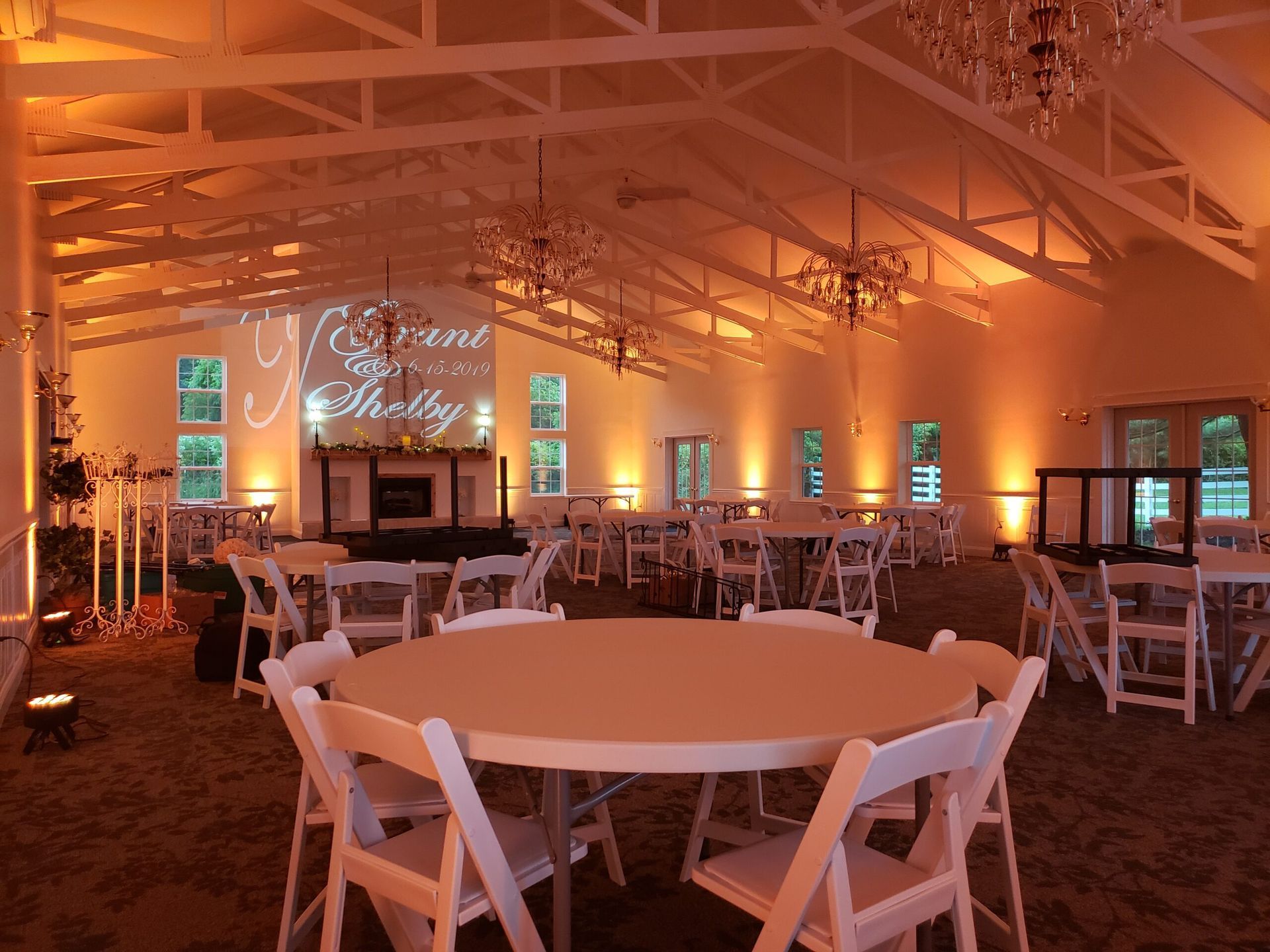 A large room with tables and chairs set up for a wedding reception.