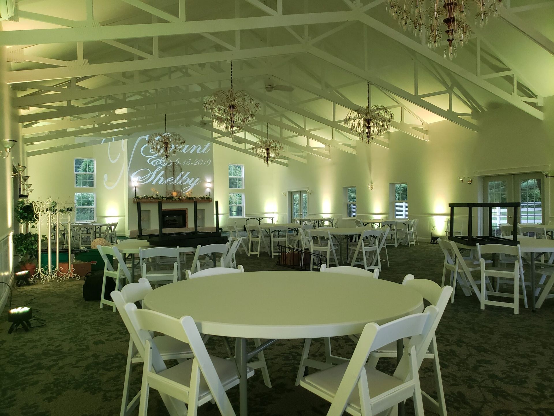 A large room with tables and chairs set up for a wedding reception.