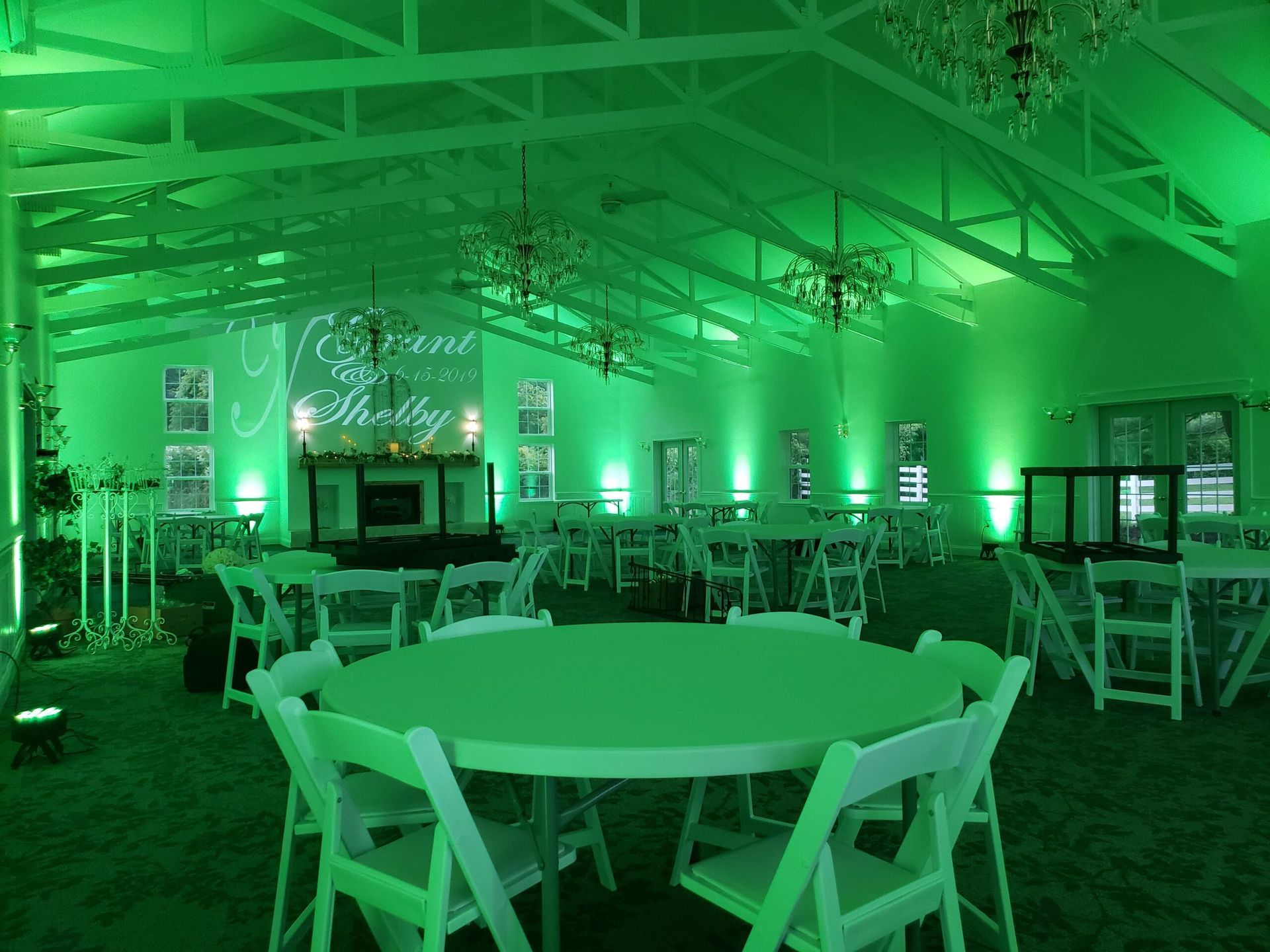 A large room with tables and chairs and green lights.