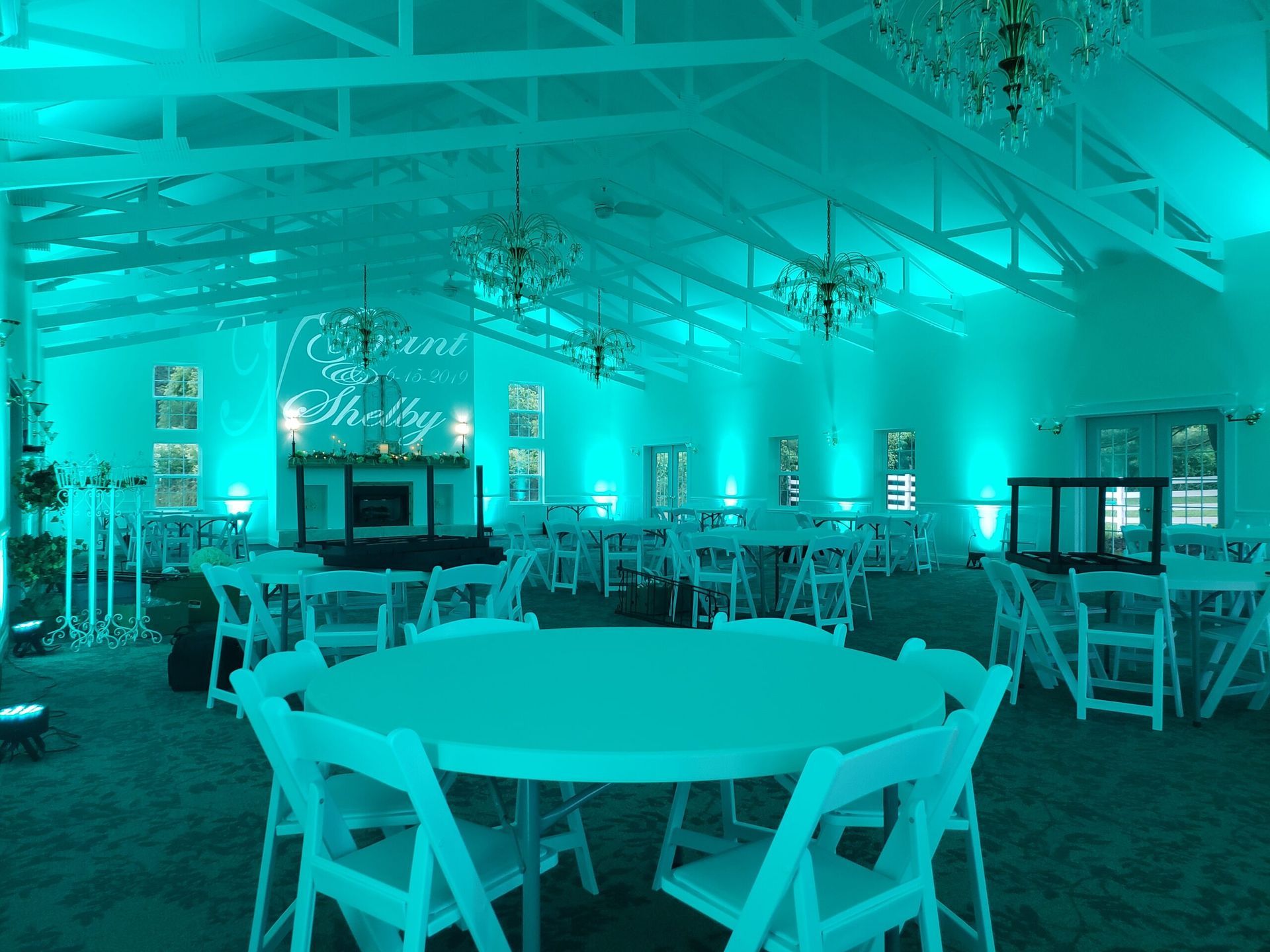 A large room with tables and chairs is lit up with blue lights.