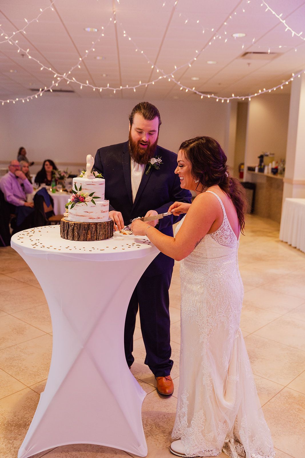 A bride and groom are cutting their wedding cake on a table.