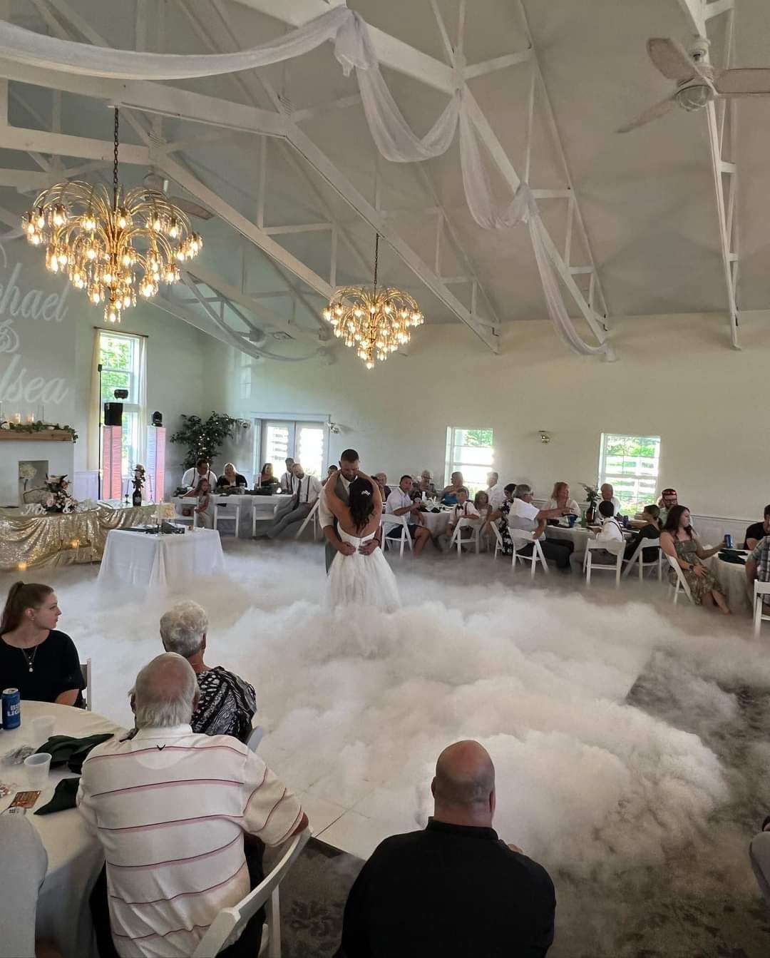 A bride and groom are dancing in front of a crowd of people