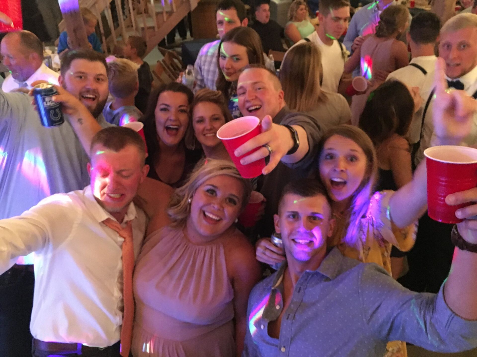 A group of people are posing for a picture at a party while holding red cups.