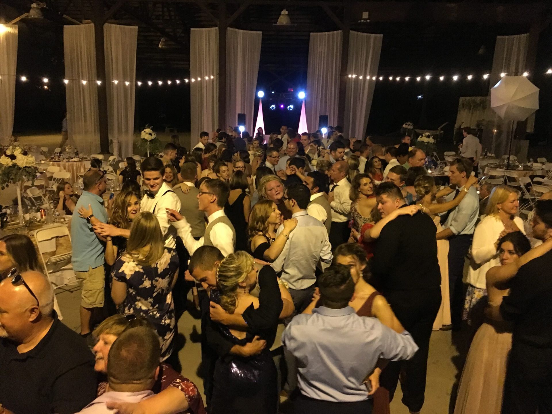 A large group of people are dancing at a wedding reception.