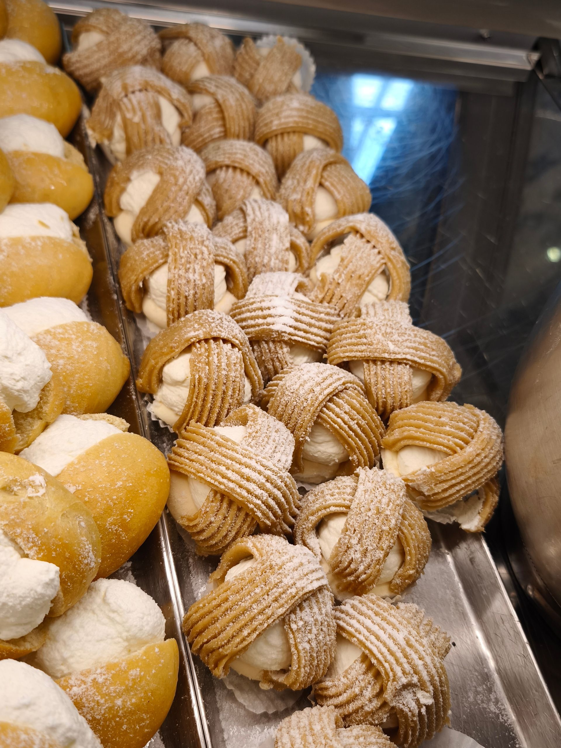 Una vetrina piena di vari tipi di pasticcini ricoperti di zucchero a velo.