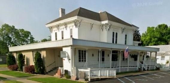 The front door of a house with a porch and plants in front of it.
