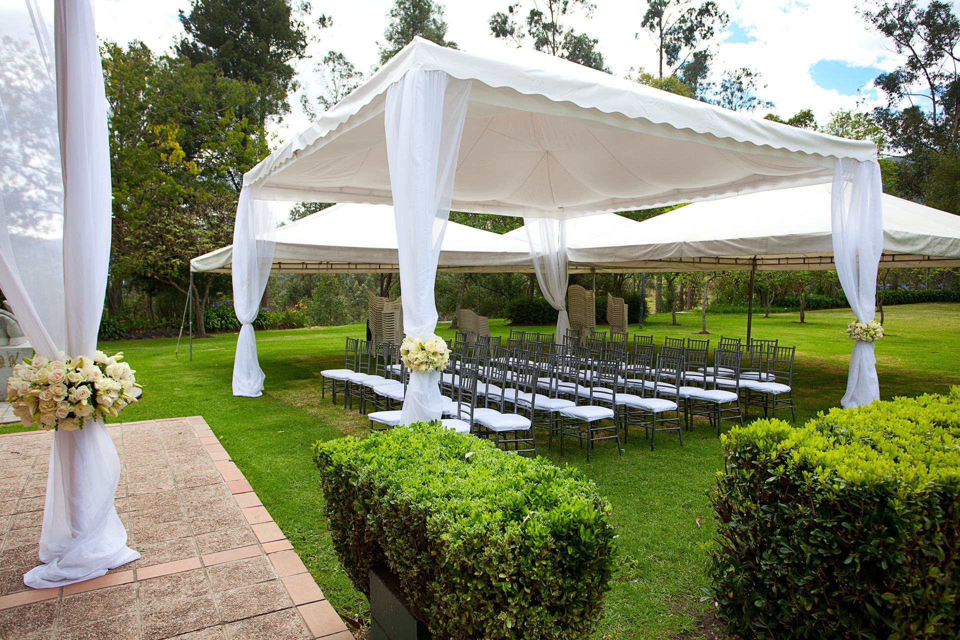 White canopy wedding reception setup with rows of chairs on a green lawn